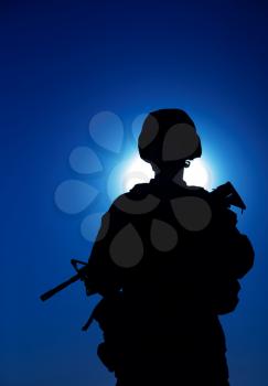 Silhouette of army infantry soldier armed assault rifle on background of night sky with moon. Special operations forces fighter in combat helmet and uniform during night mission, military sentry duty