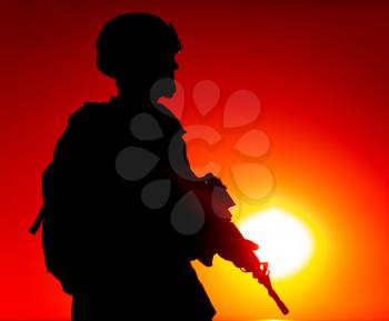 Silhouette of army special forces rifleman, Marines, coast guard or anti-terrorist squad soldier in ammunition and helmet, armed service rifle, standing on ocean shore, patrolling seacoast at sunset