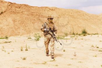 Equipped special forces soldier walks across desert. Anti-terror operation concept.