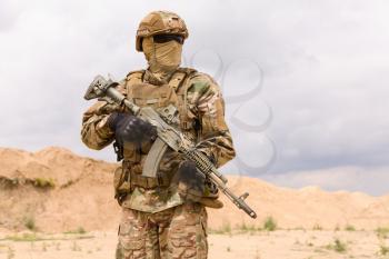 Armed special forces soldier in camouflage holding rifle close-up