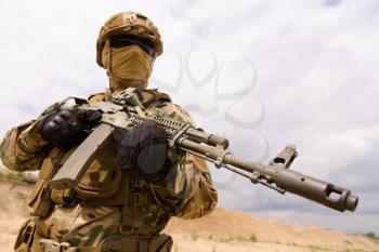 Army soldier holding rifle against sky background, copy space for text