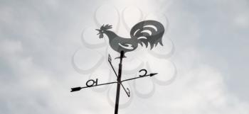 Weather vane against the evening sky and clouds