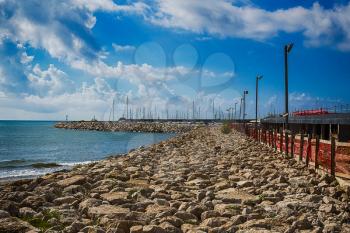 Bright sea pier  with colorful clouds over azure waters