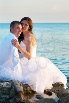 Beautiful wedding couple- bride and groom hugging at the beach. Just married