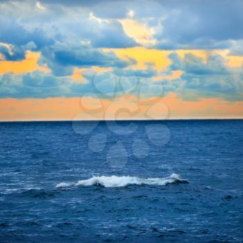 Big wave, colorful sunset over the sea with blue sky and clouds