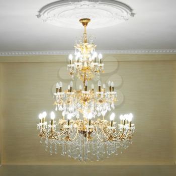 Beautiful crystal ancient chandelier in a hall. Lamp with soft yellow light