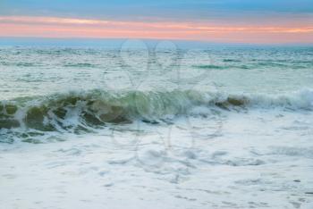 Sea landscape with big waves against sunset