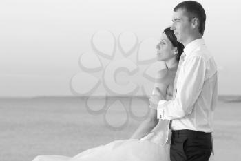Beautiful wedding couple- bride and groom hugging at the beach. Just married. Black and white