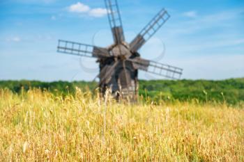 Old mill on the yellow wheat field with blue sky