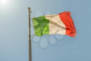 Waving Italian flag on the blue sky background