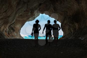 People in the big cave, view from inside. Mediterranean coast, Sardinia, Italy.