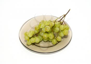 Green grapes on the plate isolated on white.