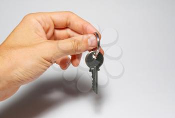 Silver key in a hand on gray background.