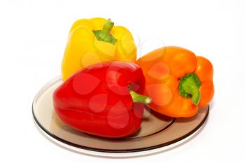 Three colored paprika on the plate on white background.