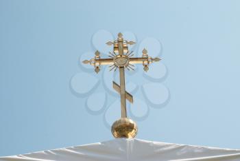 Golden orthodox cross with blue sky background