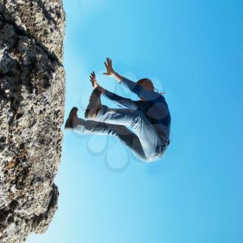 Falling down man from the rock with blue background