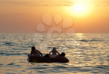 People on the raft with sea's sunset 