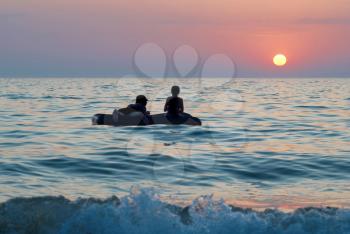 People on the raft with sea's sunset 