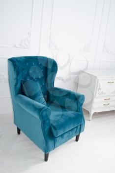 Luxurious velvet armchair of the sea waves color in a white interior.