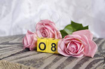 8 March symbol and roses. Figure of eight on cubes with roses on wooden background. Happy woman's day design. Can be used as a greeting card for international Woman's Day on 8 March.