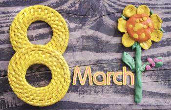 8 March symbol and handmade plasticine flower on wooden background. Happy woman's day design. Can be used as a decorative greeting card or postcard for international Woman's Day on 8 March.