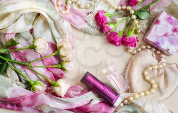 Photocomposition in a gentle vintage style in pastel colors. Tea and pink roses lie on a silk scarf, surrounded by pearls, lipsticks, perfumes.