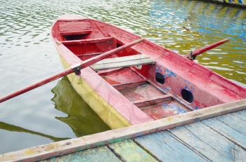 Traditional colorful wooden boat on water. Docked boat at a lake.