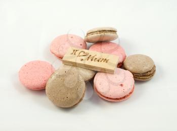 Chokolate and pink macarons chaotically arranged and a board with the inscription I love mum. A Happy Mother's Day theme.
