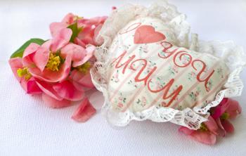 Textile handmade white heart with the inscription I love mum and red roses petals on a white background. A Happy Mother's Day theme.