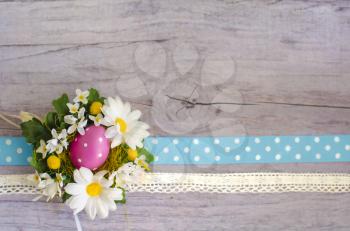Wooden textured surface with chamomiles, Easter egg and spotted ribbon. Beautiful template for your design.