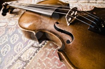 Still life with vintage violin. Closeup of old wooden violin. Stringed music instrument on abstract background.
