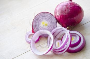 Sliced fresh red onion isolated on wooden background. Full and choppen onion. Closeup shoot.