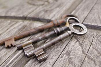 Vintage keys on old wooden background. Close-up. Three old, rustic keys on the table. 