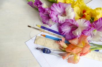 Bouquet of gladiolus flowers and school supplies. Back to school. Notebooks, pens, ruler and flowers on the desk.