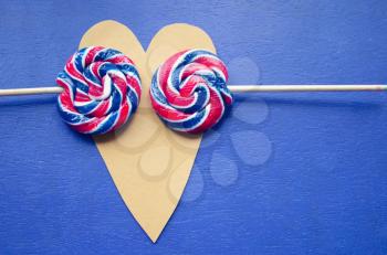 andy swirl rainbow round two lollipops on heart-shaped. Candy stripes on a stick on blue background. Love concept. February 14. Holidays happy valentines day celebration.. Valentine theme.