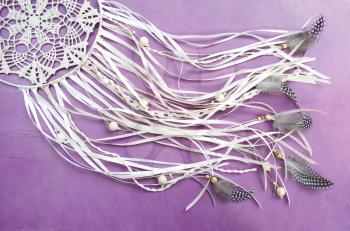 Dreamcatcher with feathers on a purple wooden background. Ethnic design, boho style, tribal symbol.