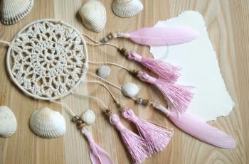 Seashells frame on wooden background with place for text. Card for a beach party, invitation, advertising.Dreamcatcher with pink feathers