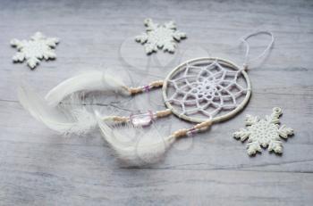 Dreamcatcher with feathers on a wooden background. Ethnic design, boho style, tribal symbol.White Christmas and New Year snowflake on a wooden vintage old background.