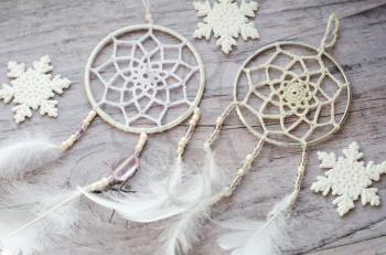 Dreamcatcher with feathers on a wooden background. Ethnic design, boho style, tribal symbol.White Christmas and New Year snowflake on a wooden vintage old background.