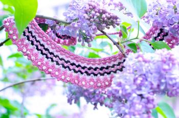 Purple lilac bush an crochet handmade accessories. Handicraft manufacturing. Spring branch of blossoming lilac.
