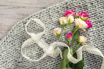 A bouquet of roses on a gray background of tender merino wool and wood.