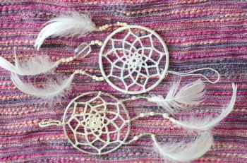 Dreamcatcher with feathers on a textile background. Ethnic design, boho style, tribal symbol.