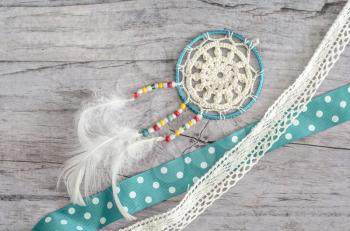 Dreamcatcher with feathers on a wooden background. Ethnic design, boho style, tribal symbol.