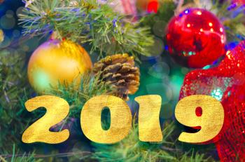 The golden inscription of 2019 on the blurred background of a Christmas tree . The greeting flyer, a banner, a postcard.