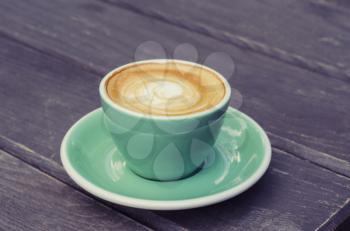Turquoise cup with latte on a wooden background. Still life in vintage style
