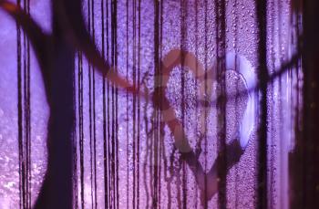 Photo of the heart on the misted window with light highlights. Art photo. Valentin day concept