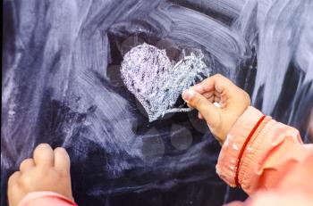 Children's drawing heart is white chalk on a black board. Valentine day is a concept photo,