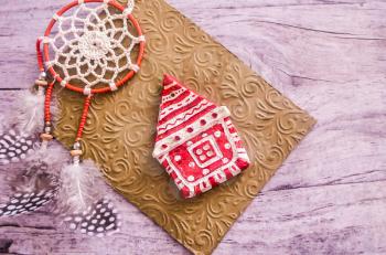 Christmas toy-house and dreamcatcher on the background of a golden embossed envelope. Christmas holidays concept.