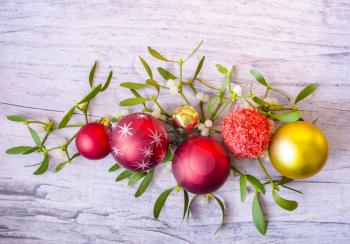 New Years and Christmas decorations with mistletoe on wooden background.The color scheme is red and gold.