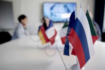 Blur effect. Meeting of management, meeting of directors. International commission, table with flags of EU, Russia and other countries.